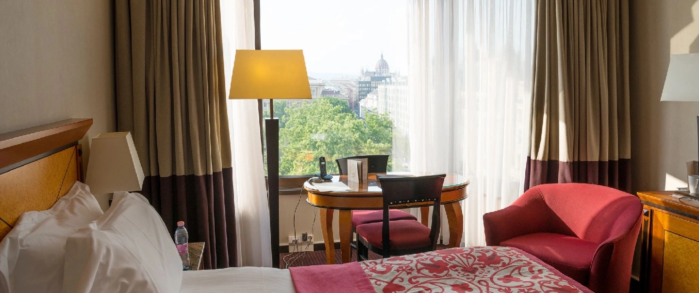 A room with a table and chairs, a lamp and a window.