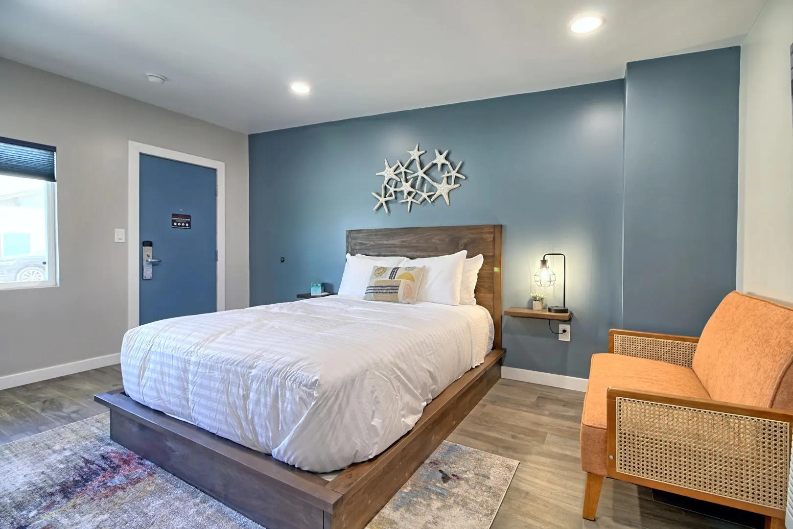 A bedroom with blue walls and wooden headboard.